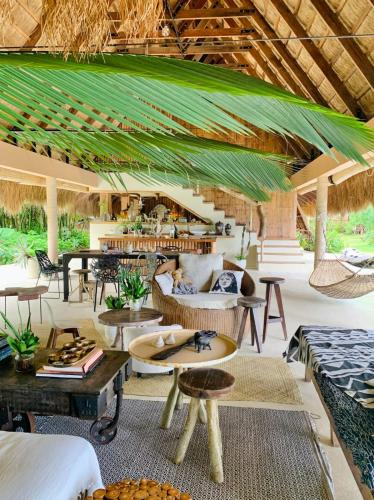 a resort lobby with tables and chairs and a roof at The Beach House Ocam Ocam in Busuanga