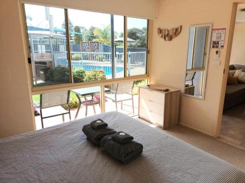 a bedroom with a bed with two towels on it at Grandeur Holiday Units in Merimbula