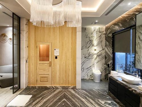 a bathroom with a wooden door and a chandelier at Domo Hotel in Taichung