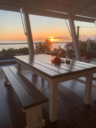 a picnic table on a balcony with the sunset at Villa Lanar'am in Bouillante