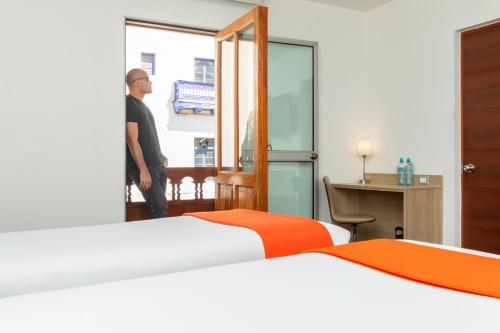 a man walking into a hotel room with two beds at Casa Andina Standard Cusco Plaza in Cusco