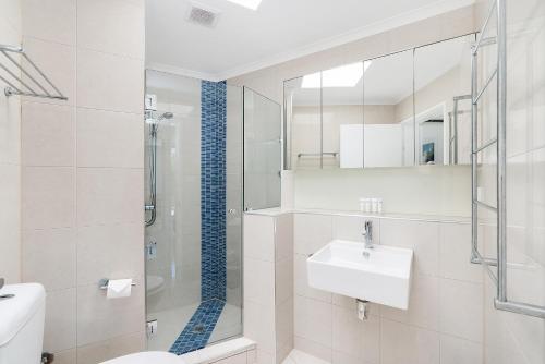a white bathroom with a sink and a shower at Paringa 2 Bedroom Top Floor Beach Front Apartment in Palm Cove