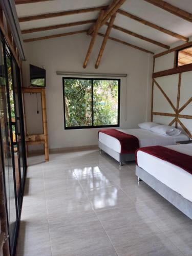 a bedroom with two beds and two windows at Las cabañas del escobo-CABAÑA GUACAMAYAS in Nimaima