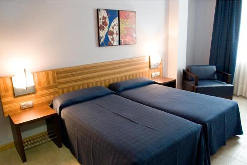 Apartamentos Turisticos Noray في أرغونيوس: غرفه فندقيه بسرير وكرسي
