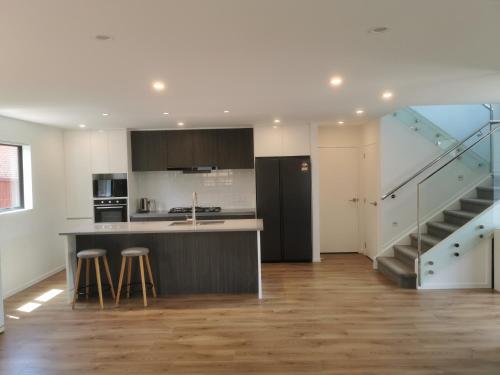 uma cozinha com um balcão e uma ilha de cozinha com bancos em Lovely House in Central Papatoetoe em Auckland