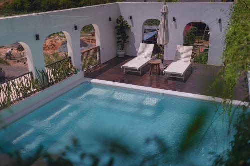 a pool on a deck with two chairs and an umbrella at Montagne Boutique in Kampot