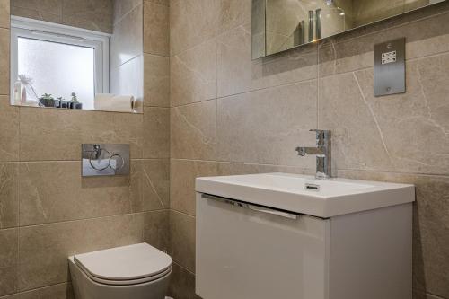 a bathroom with a toilet and a sink at Dainty 2BD Flat in Greater London in London