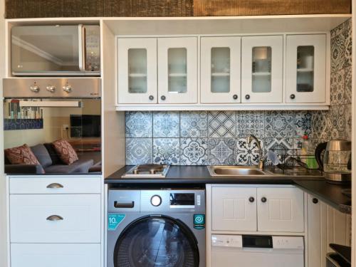 uma cozinha com uma máquina de lavar roupa e um lavatório em Apartment18Lifestyle Gordons Bay Beachfront em Gordonʼs Bay