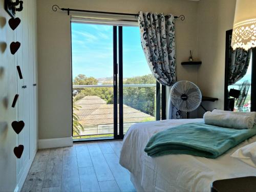 a bedroom with a bed and a large window at Apartment18Lifestyle Gordons Bay Beachfront in Gordonʼs Bay