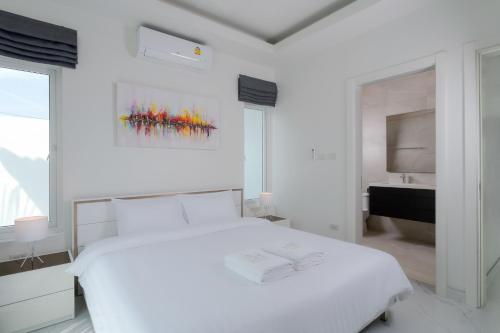 a white bedroom with a white bed and a bathroom at Orchid Paradise Homes OPV428 in Hua Hin