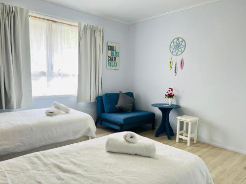 1 dormitorio con 2 camas y silla azul en La Sol - All you need for a stay, close to town, University & Cambridge, en Hamilton