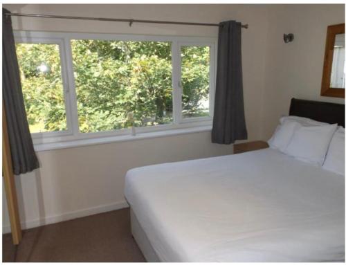 1 dormitorio con cama blanca y ventana en Atlantic Retreat, en Newquay