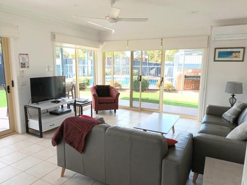 a living room with a couch and a tv at Grandeur Holiday Units in Merimbula