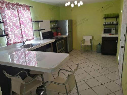 una cocina con fregadero y algunas sillas. en Casa Tecalai 5 en San Carlos