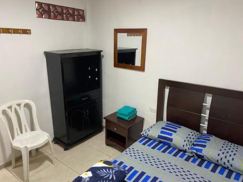 a bedroom with a bed and a chair and a mirror at Habitación independiente Baño exterior in Armenia