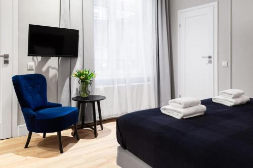 a bedroom with a blue bed and a chair and a television at Househost Apartment: Bonerowska 5/15 in Krakow