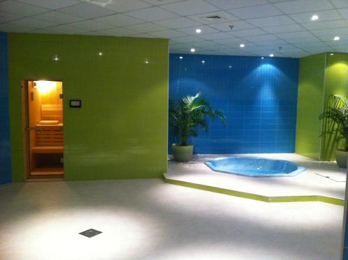 a bathroom with a tub and a green wall at Wakra Inn Hotel Apartments in Al Wakrah