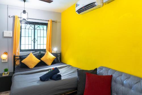 a yellow room with a bed and a couch at Whoopers Hostel Palolem in Palolem