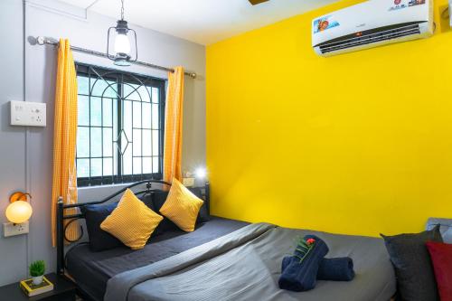 a bedroom with a bed with a yellow wall at Whoopers Hostel Palolem in Palolem