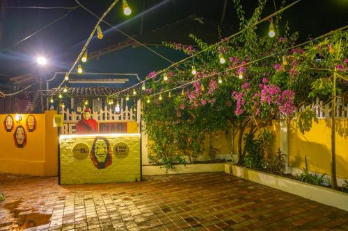 a patio with lights and flowers and plants at Whoopers Hostel Palolem in Palolem