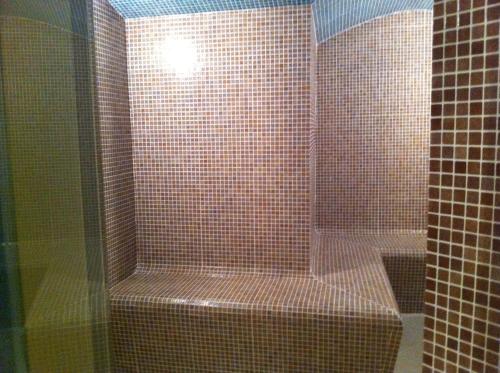 a bathroom with a shower with a toilet and a glass door at Wakra Inn Hotel Apartments in Al Wakrah