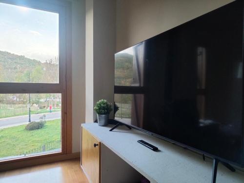 a living room with a large television and a window at Los Cachorros in El Pueyo de Jaca
