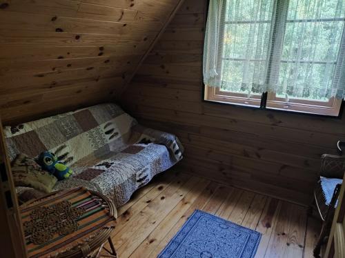 a room with a couch in a log cabin at Rajski Staw in Zajki