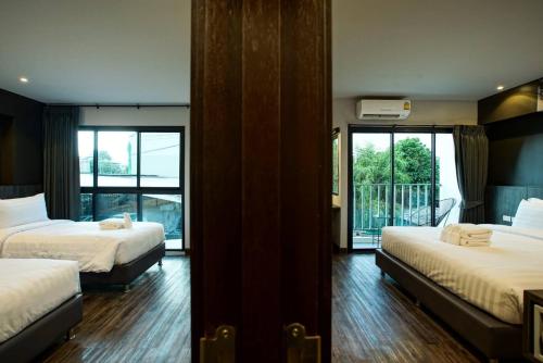a hotel room with two beds and a balcony at Sleep Mai Thapae Chiang Mai Old City Lifestyle Hotel - SHA Plus in Chiang Mai