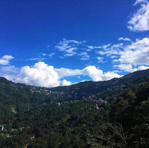 una vista de una montaña con un cielo azul y nubes en House of Nomad en Gangtok