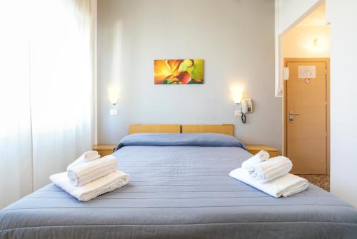 a bedroom with a blue bed with white towels on it at Hotel Ausonia in Rimini