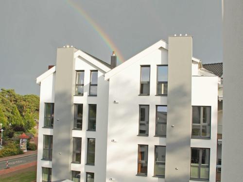 a rainbow in the sky above a white building at Strandvilla Baabe - Maisonette "Sonnenwiege" mit Sauna und Whirlpool in Baabe