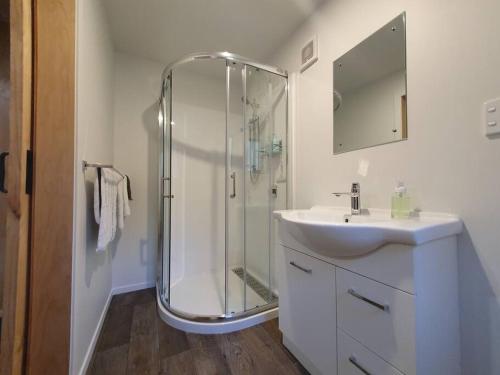 a bathroom with a shower and a sink at Glenwood Akaroa Bush Retreat - Totara Hut in Akaroa