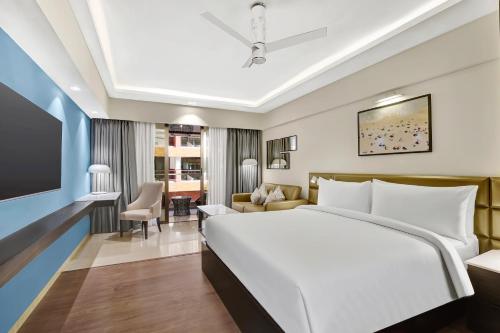 Radisson Resort Goa Baga في باغا: غرفة نوم مع سرير وغرفة معيشة