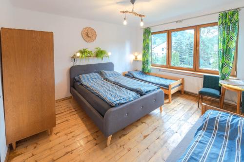 a bedroom with a bed and a desk and windows at Apartament Latynoski z ogrodem - Dream Apart in Ustroń