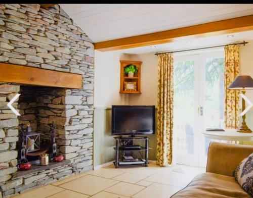 a living room with a tv and a stone fireplace at Dove Cot country cottage Ambleside in Ambleside