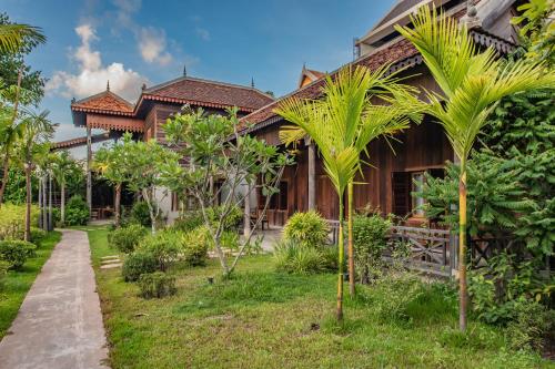 a house with palm trees in front of it at Phum Khmer Lodge - Village Cambodian Lodge in Siem Reap