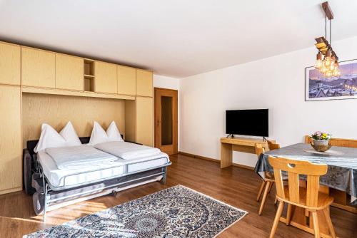 een slaapkamer met een bed, een tafel en een televisie bij Villa Erina App A2 in Ortisei