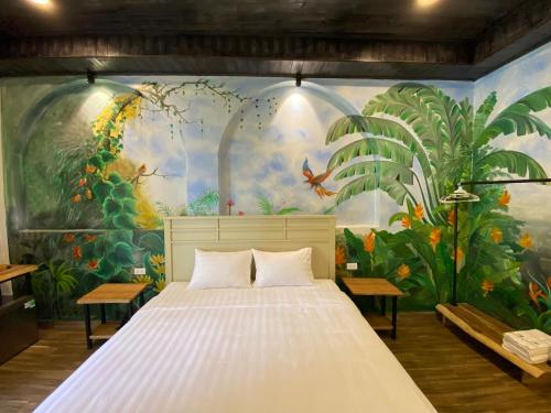 a bedroom with a large white bed in front of a mural at Cerf Volant Soc Son in Sóc Sơn