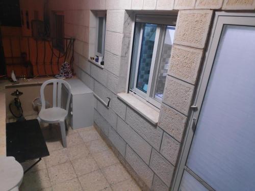 Baño pequeño con ventana y silla en Fully Furnished Apartment in Bethlehem Center en Bethlehem
