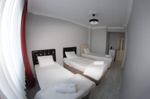 Habitación con 3 camas y almohadas blancas. en Delpina APART - Doğa içinde deniz manzaralı en Pazar