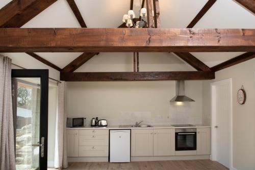 uma cozinha com armários brancos e um tecto de madeira em K2Cottages 