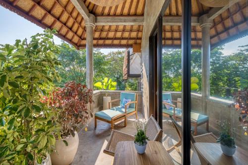 an outdoor patio with tables and chairs and plants at Leafy Home Canggu in Canggu
