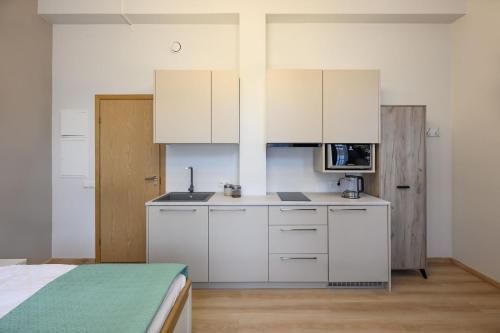 a kitchen with white cabinets and a bed in a room at Kastanimaja Apartments in Tartu