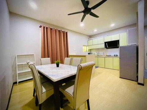 un tavolo da pranzo con sedie e un ventilatore a soffitto di NurHumaira Homestay a Pantai Cenang