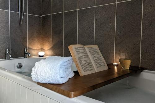 eine Badewanne mit zwei Büchern auf einem Holzregal in der Unterkunft Baker's Cottage, Urban Spa and Garden Bar in Evesham