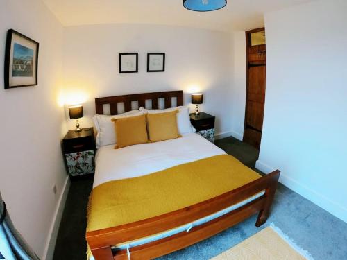 ein Schlafzimmer mit einem großen Bett und einer gelben Decke in der Unterkunft Baker's Cottage, Urban Spa and Garden Bar in Evesham
