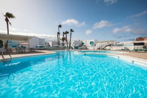 卡萊塔德菲斯泰的住宿－Smy Tahona Fuerteventura，一座种植了棕榈树和建筑的大型蓝色游泳池