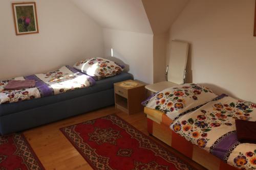 a bedroom with two beds and a couch and a rug at Penzión Dúha in Dedinky
