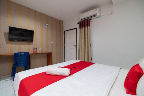a bedroom with a red and white bed and a tv at RedDoorz near RSIA Andini Pekanbaru in Pekanbaru