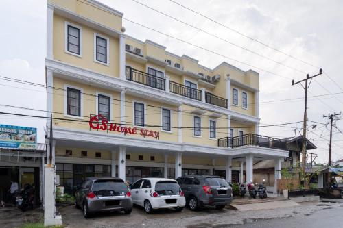 a large yellow building with cars parked in front of it at RedDoorz near RSIA Andini Pekanbaru in Pekanbaru